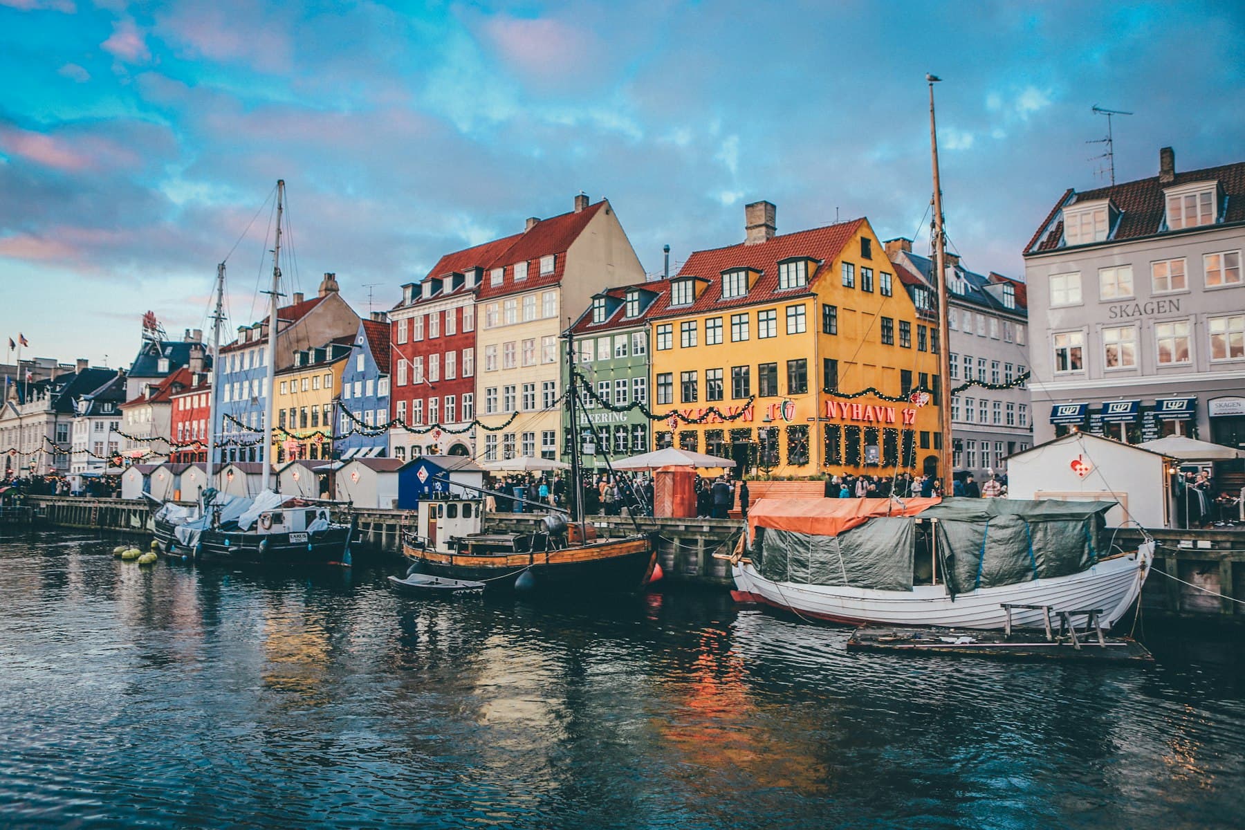 Træskibe fortøjet langs kanalen foran de farvede huse i Nyhavn i København